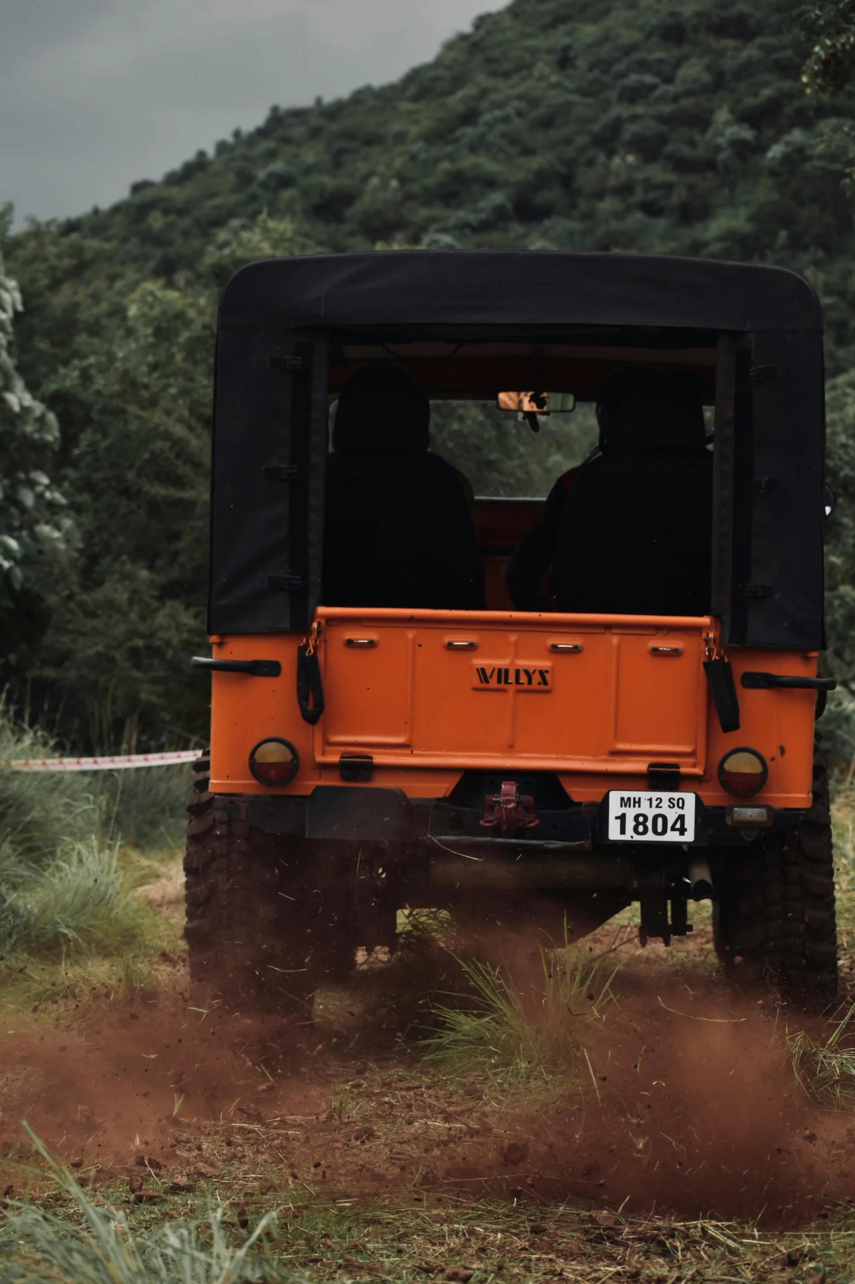 an orange truck driving down a dirt road